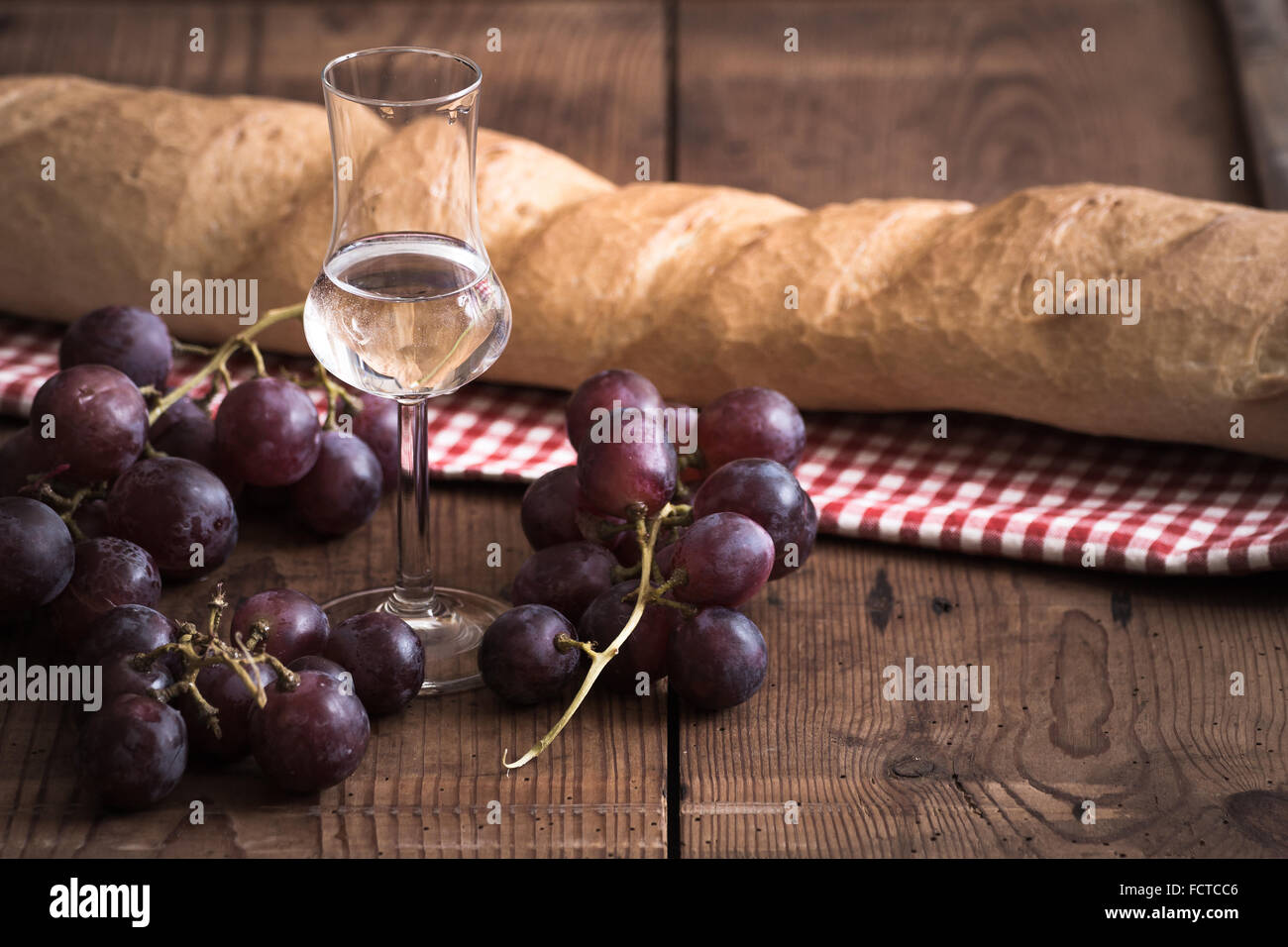 italienischen Grappa mit Trauben und Brot auf Holztisch Stockfoto