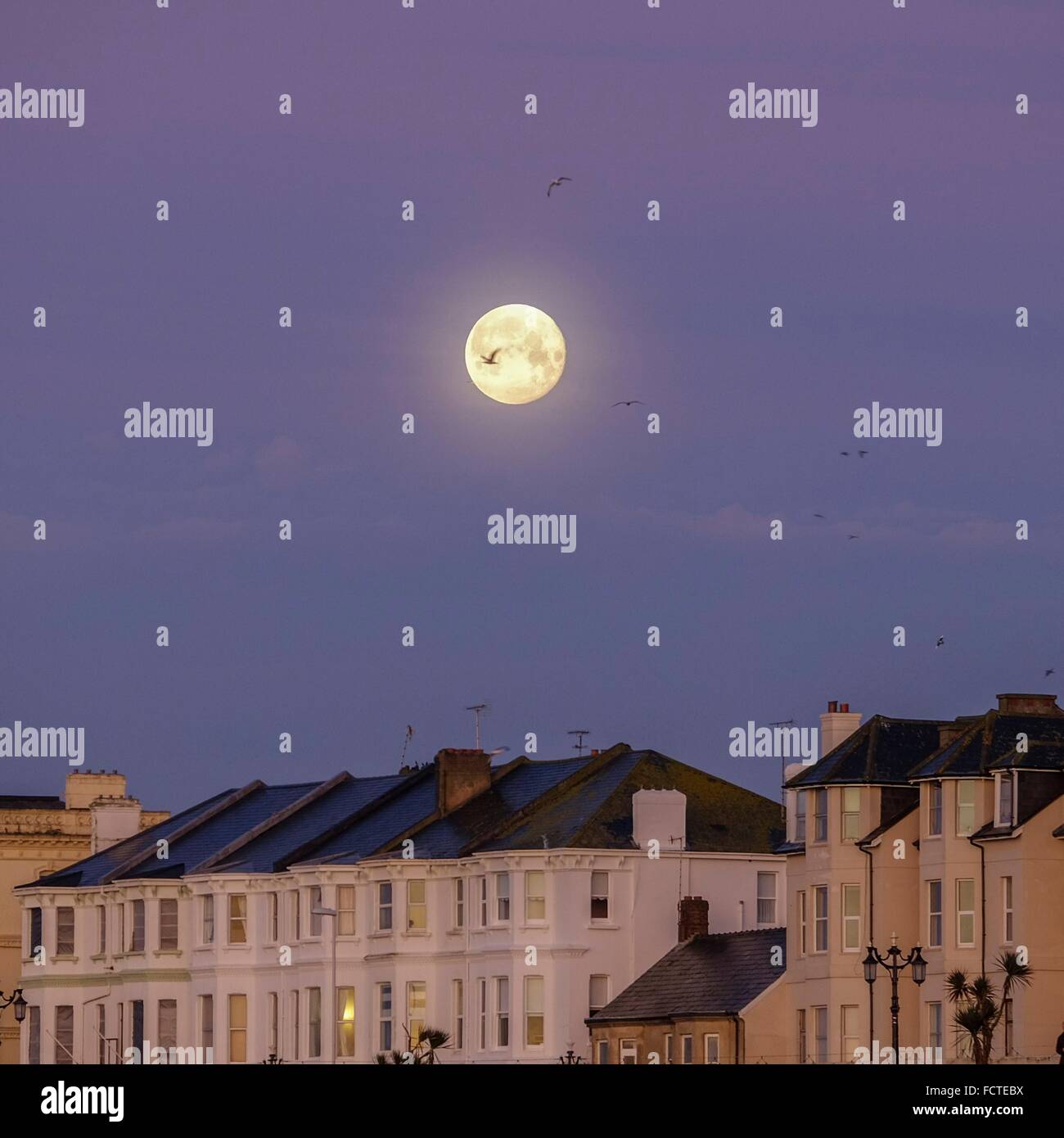 25.01.2016 am Worthing Pier, Worthing. Der Mond macht über den georgischen Terrassen auf Worthing direkt am Meer in einem tiefen rot/rosa Himmel. Bild von Julie Edwards/Alamy Live-Nachrichten Stockfoto