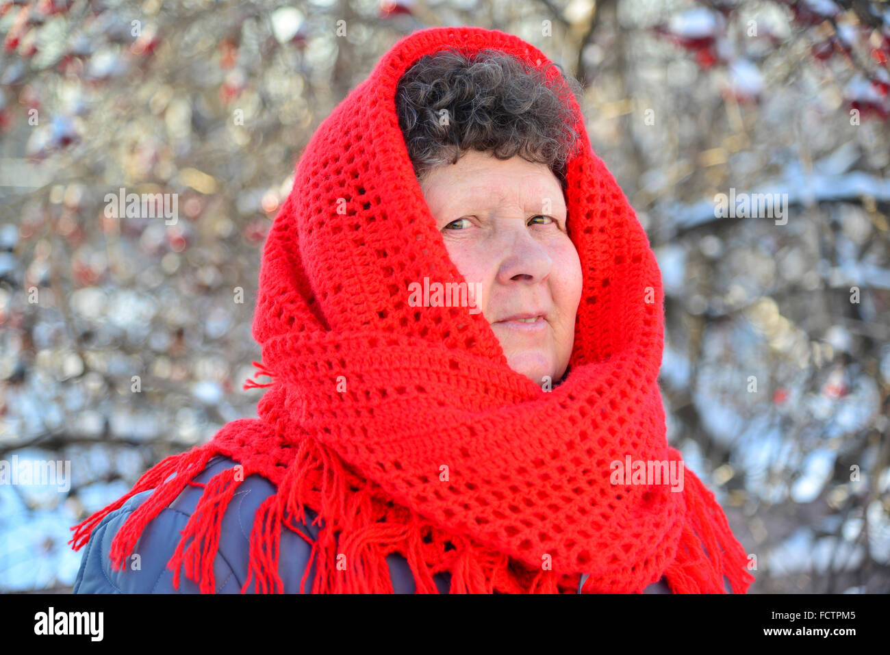 Ältere Frau im roten Schal auf dem Kopf im freien Stockfoto