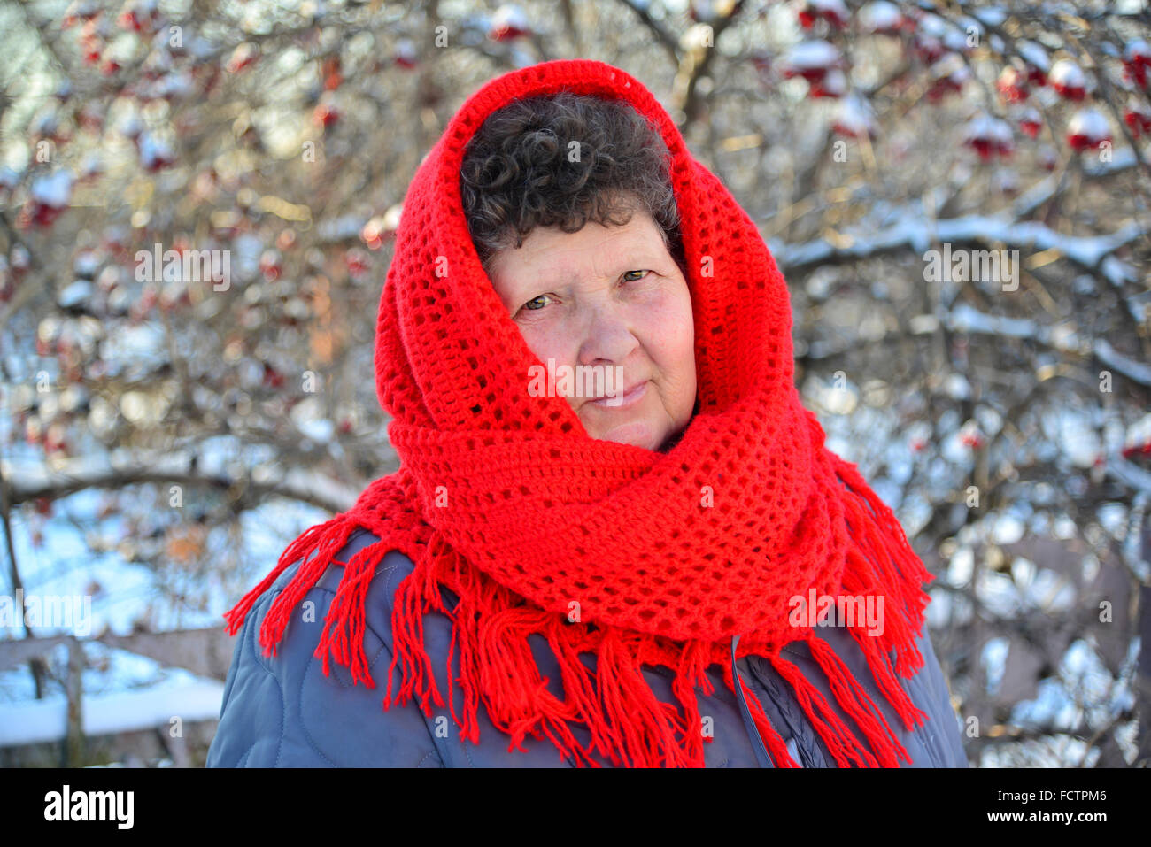 Ältere Frau im roten Schal auf dem Kopf im freien Stockfoto