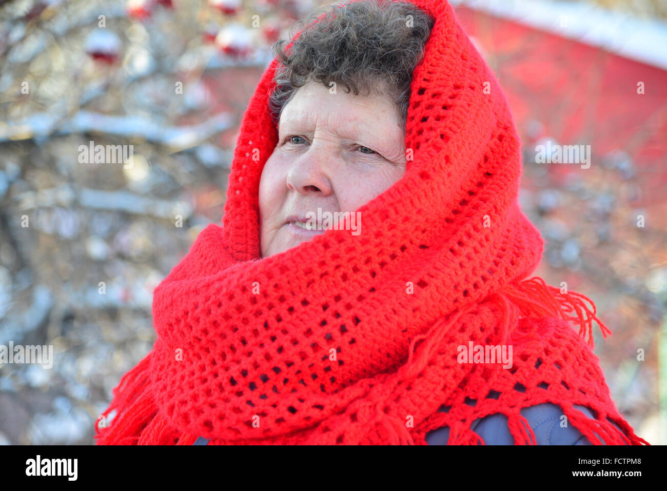 Ältere Frau im roten Schal auf dem Kopf im freien Stockfoto