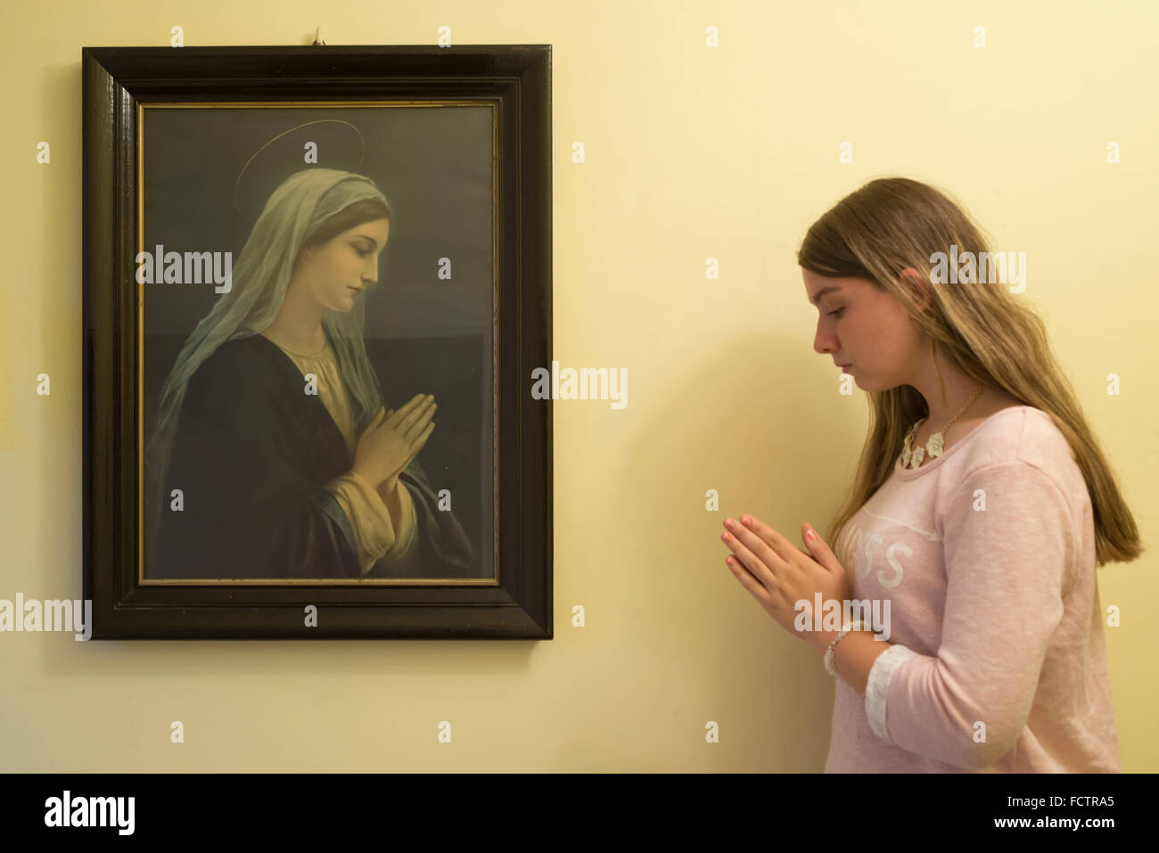 Junge Frau beten wie das Porträt der seligen Jungfrau Maria neben an einer Wand in einem Kloster, Schlesien, Polen Stockfoto