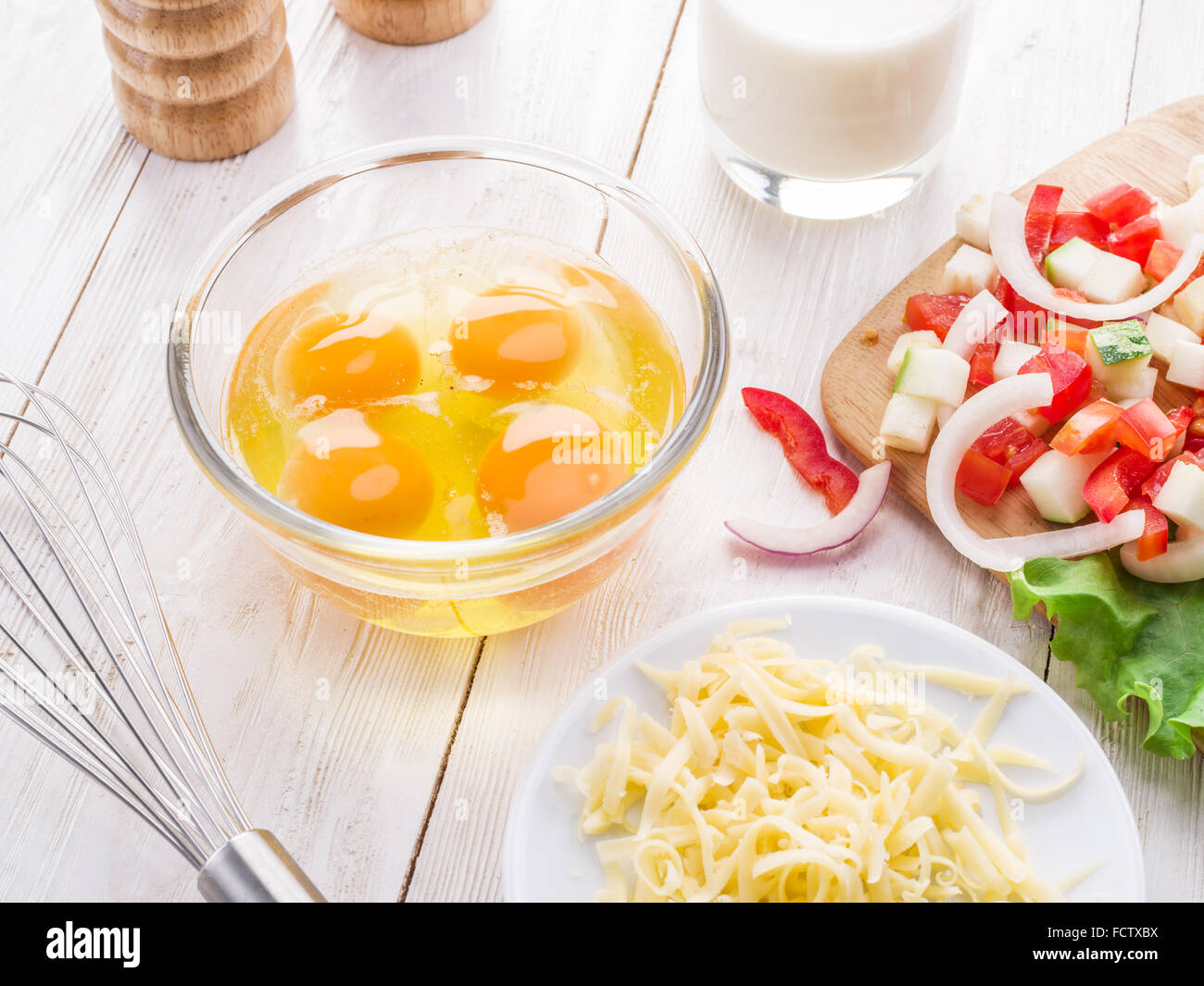 Omelette-Zutaten: Eiern, frisch geschnittene Gemüse, Milch und Käse auf dem Holztisch. Stockfoto