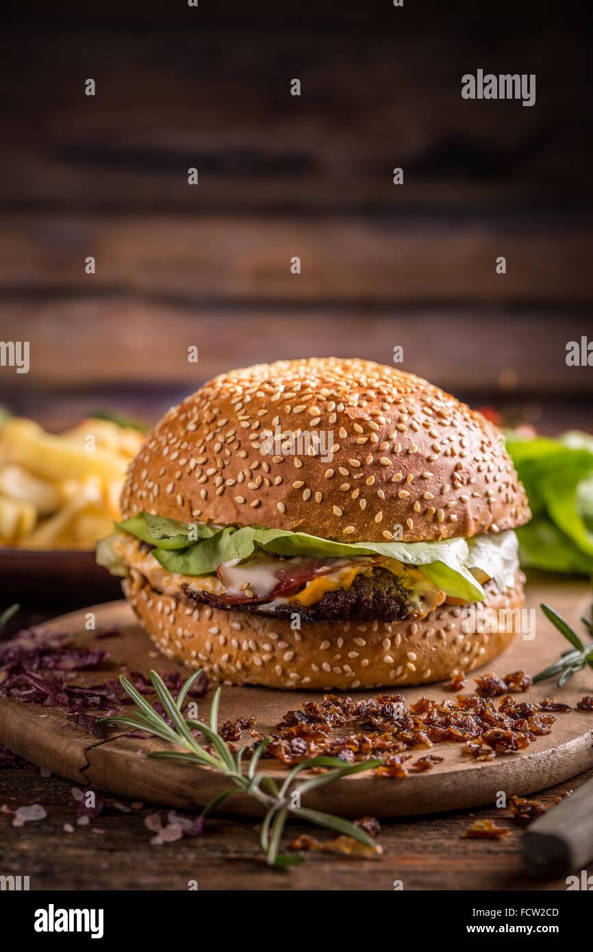 Leckere Burger mit Rindfleisch, Zwiebeln, Käse und Salat Stockfoto