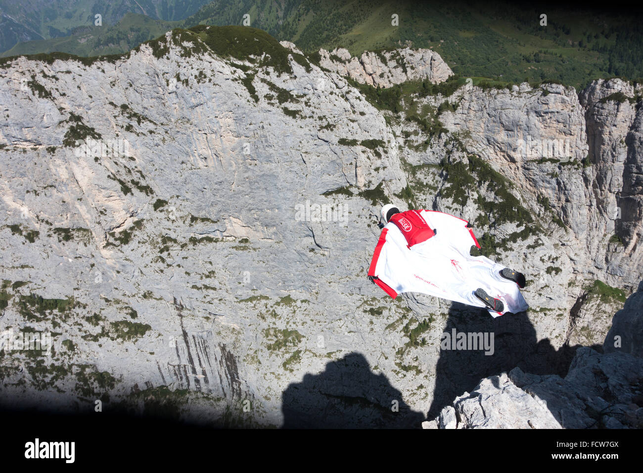 Crazy Base Jumper fliegen innerhalb seiner Wingsuit entlang einer Felswand. Dabei hat er die hochfliegenden mit 100 km/h vorwärts und hat einen grossen Ansturm. Stockfoto