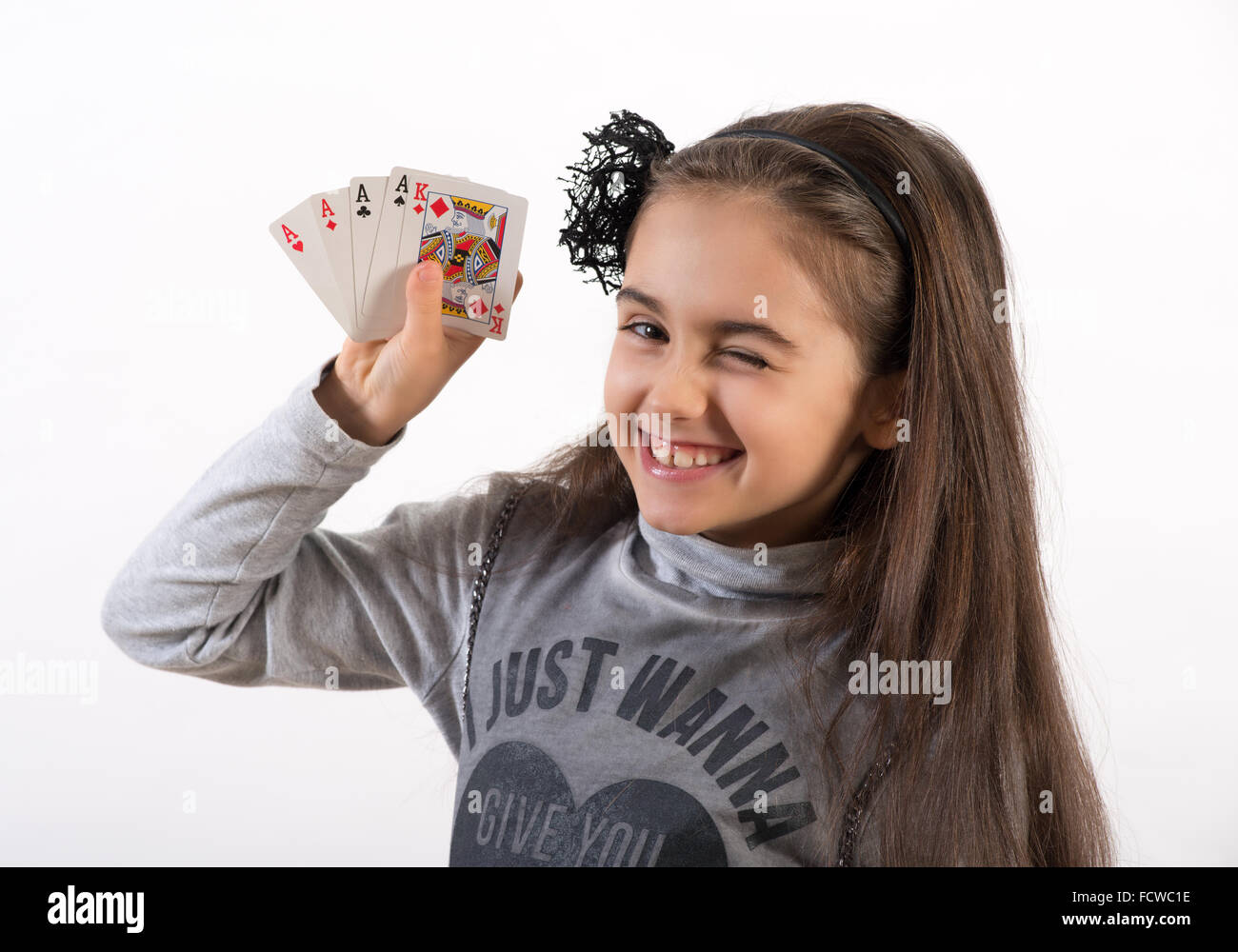 Hübsche kleine Glückspilz zwinkert in die Kamera, wie sie ihr Pokerhand vier Asse und ein König zeigt Stockfoto