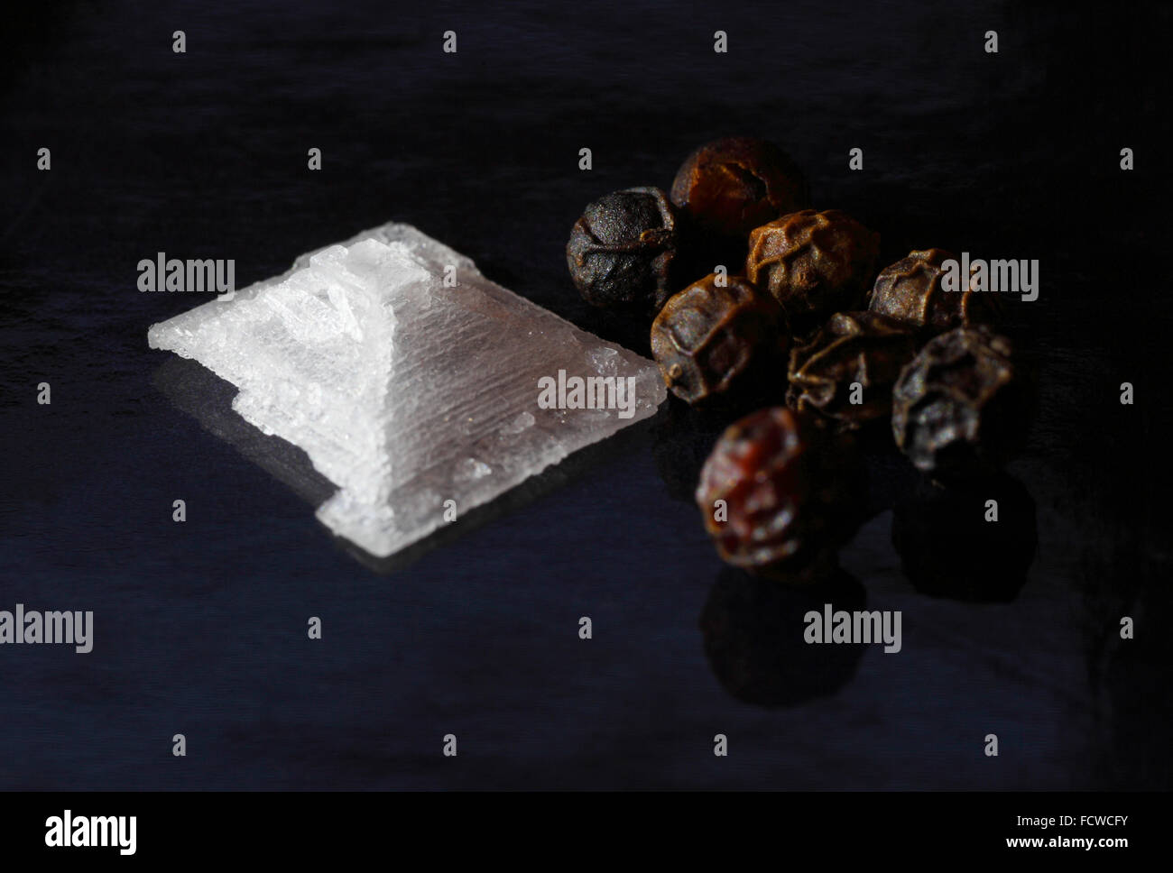 Meer-Salz-Kristall und ganze schwarze Pfefferkörner. Stockfoto