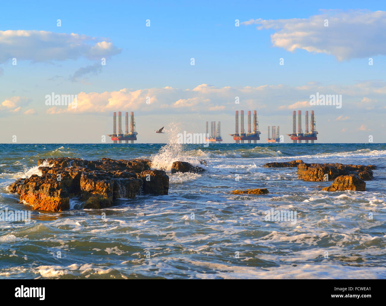Sonnenuntergang über dem tosenden Meer. Meer-Station der Gasproduktion. Bohrplattformen im Meer bei Sonnenuntergang vor blauem Himmel Stockfoto