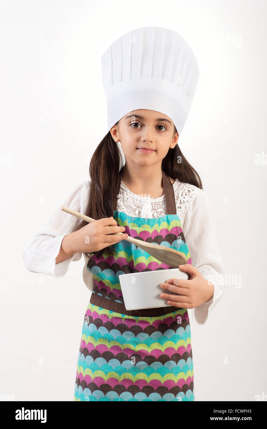 Niedlich kleine Köchin oder Koch in einer bunten Schürze und Haube stehend Stockfoto