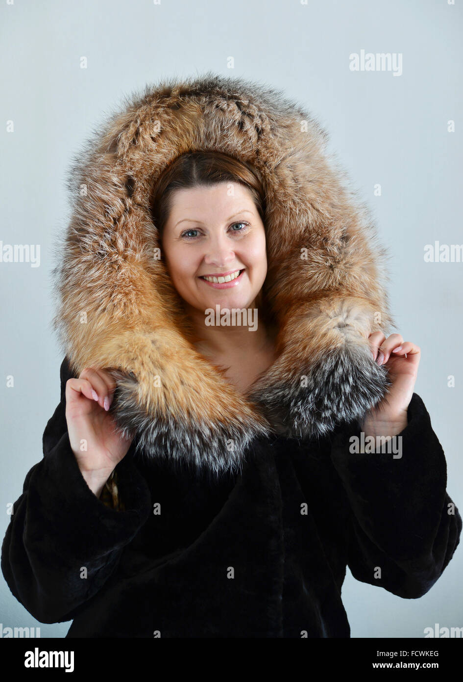 Frau in einem Pelzmantel auf hellem Hintergrund Stockfoto