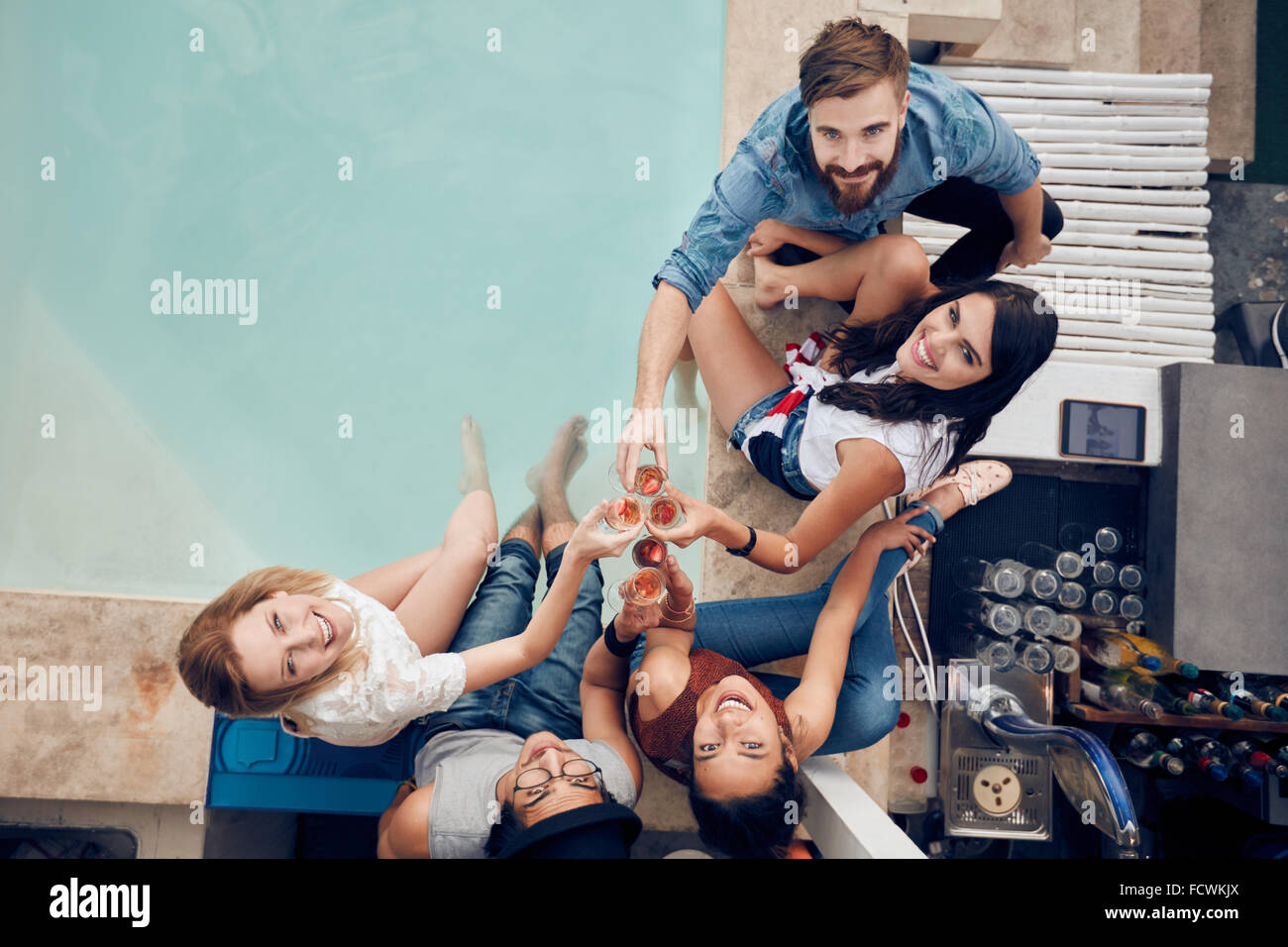 Draufsicht der Gruppe von Freunden auf Party von einem Schwimmbad Toasten und blickte in die Kamera Lächeln. Gemischtrassig junge peopl Stockfoto