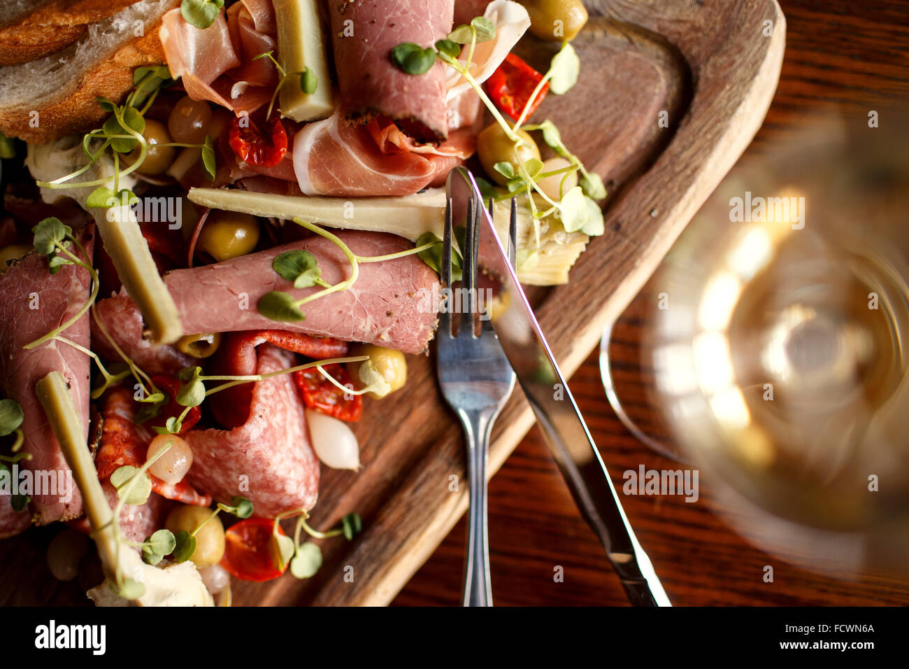 Eine mediterrane Board mit Schinken, Brot, Oliven, Artischocken, sonnengetrocknete Tomate und eingelegte Zwiebeln Stockfoto