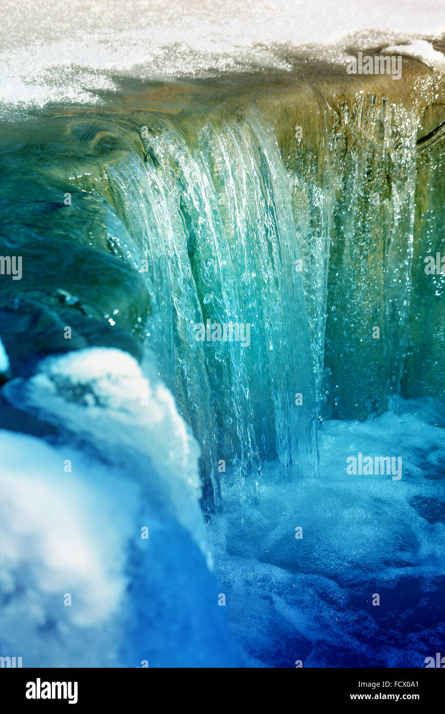 Schöne kleine Winter Creek Wasserfall fotografiert Closeup auf einem Hintergrund von Schnee und Eis Stockfoto