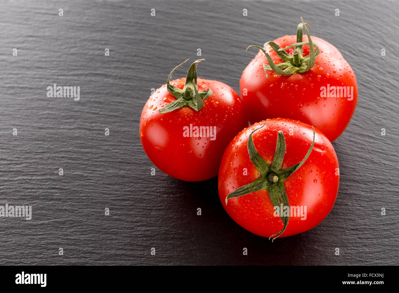 Tomaten auf einem dunklen Stein Hintergrund. Stockfoto