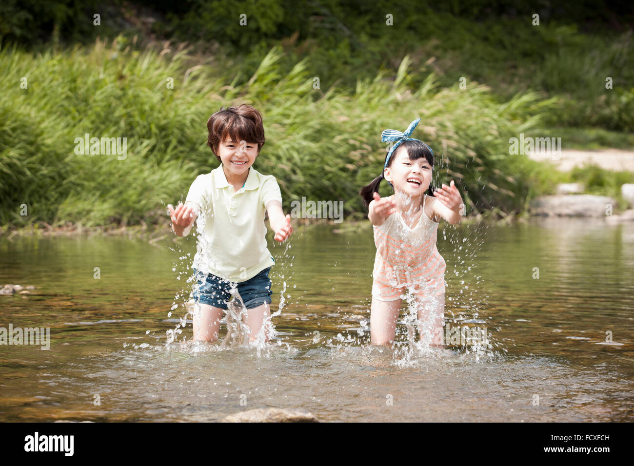 Junge und ein Mädchen spielen im Wasser des Baches genießen ihren Sommerurlaub Stockfoto