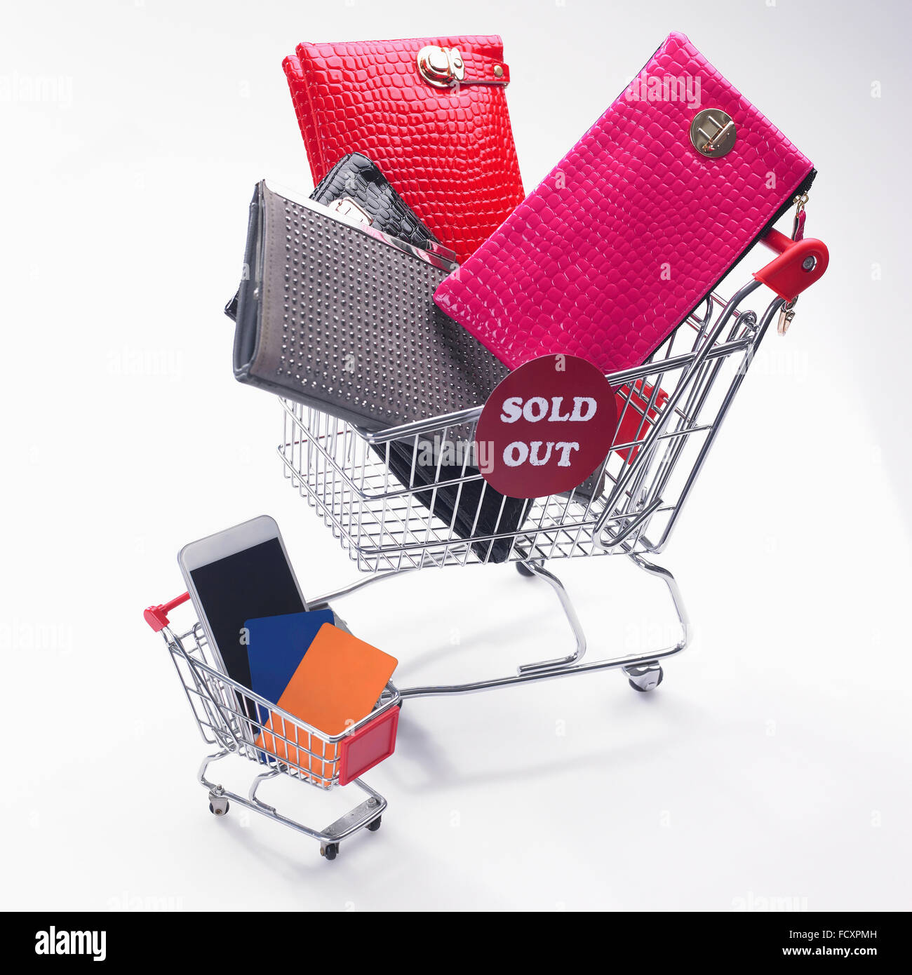 Kreditkarte und Smartphone in einem Warenkorb, verschiedene Taschen in einen Einkaufswagen mit ausverkauft Schild Stockfoto