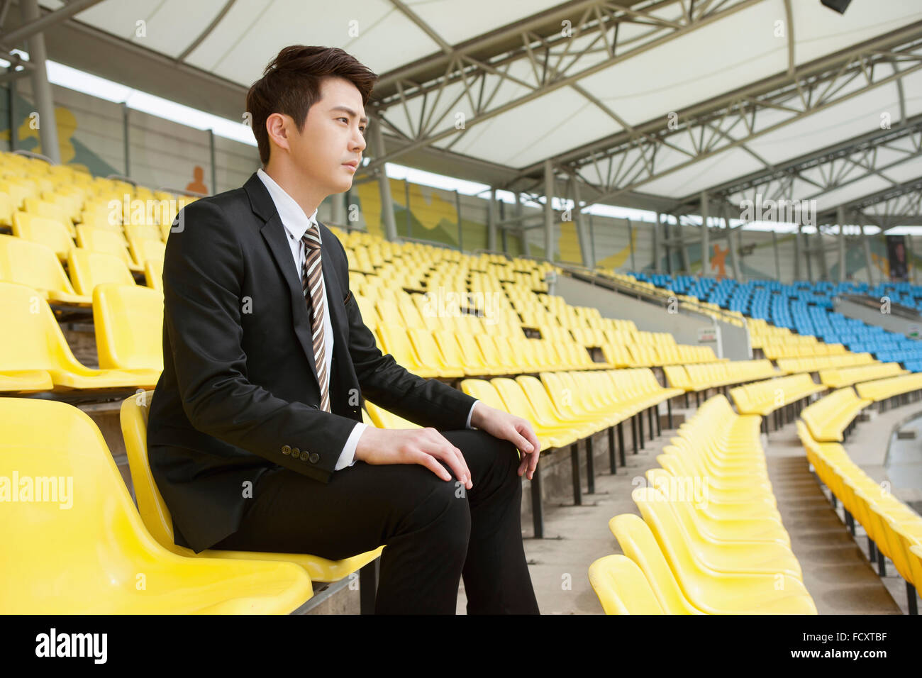 Seitenansicht der junge Geschäftsmann auf Stadion Sitz sitzen Stockfoto