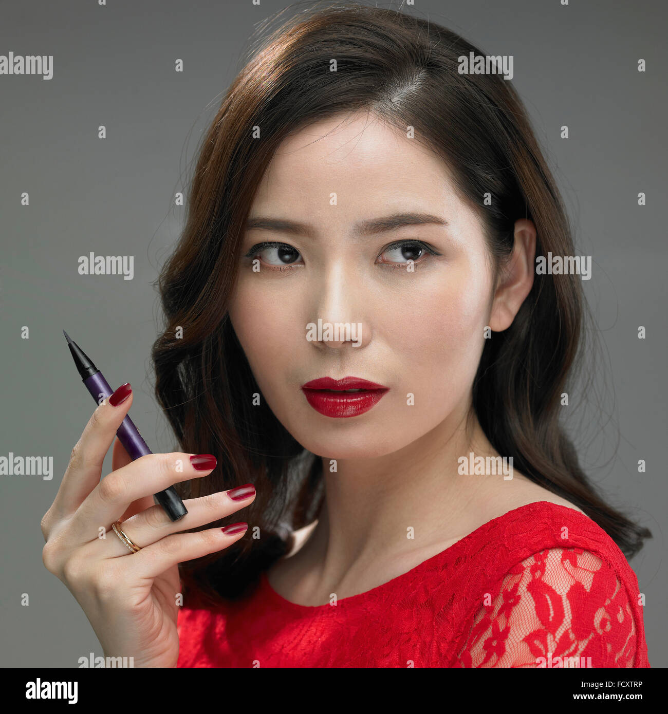 Porträt der jungen Frau mit roten Lippen und roten Bluse posiert mit eyeliner Stockfoto