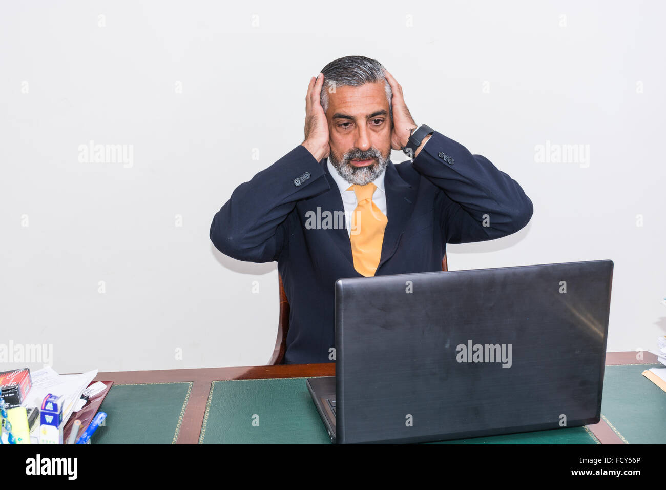 Verzweifelter Geschäftsmann. Allein in seinem Büro, vor dem Schreibtisch mit dem Computer, es Panik, Depression. Stockfoto