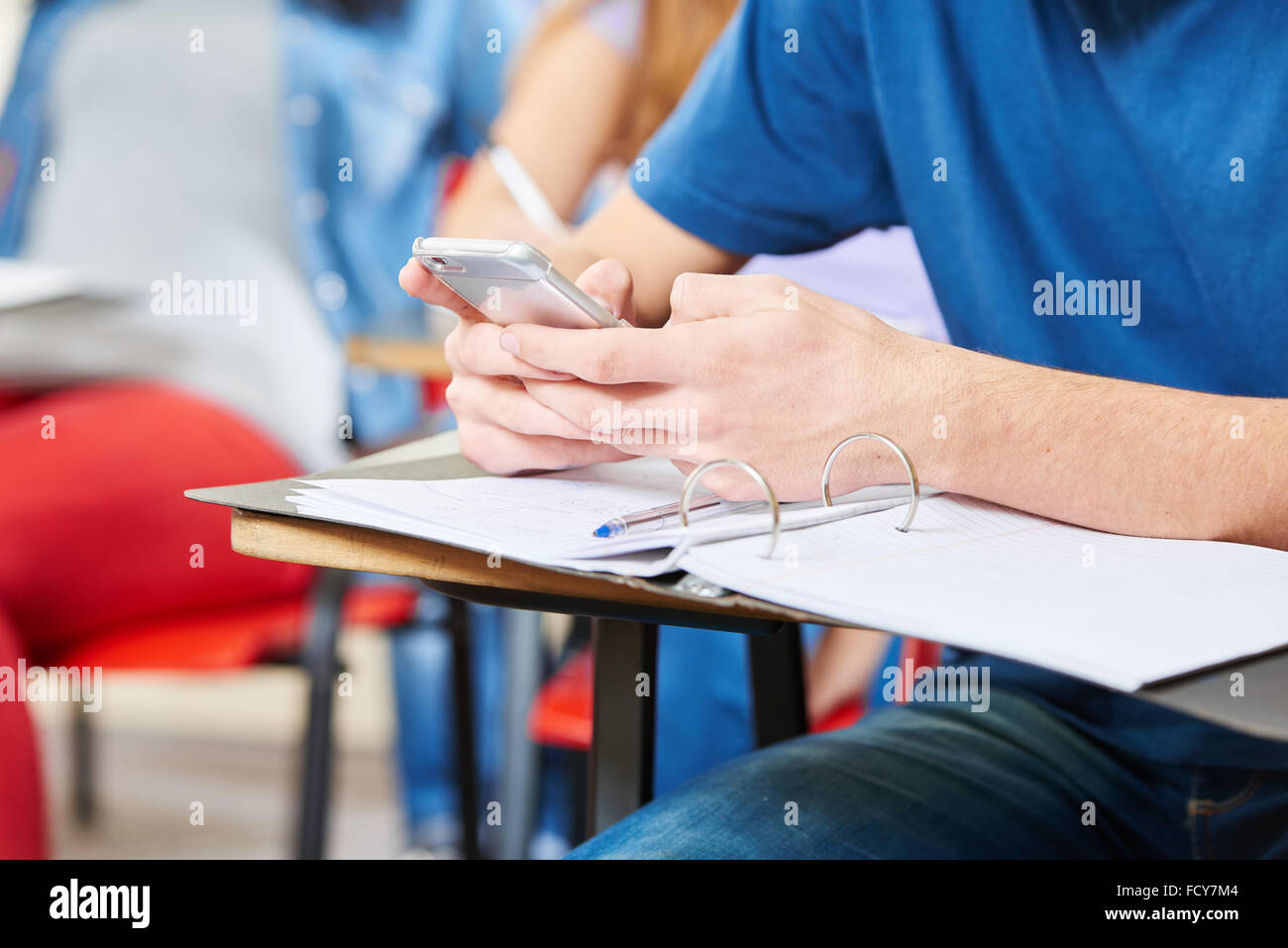 Student SMS im Unterricht mit seinem Smartphone in der Schule Stockfoto