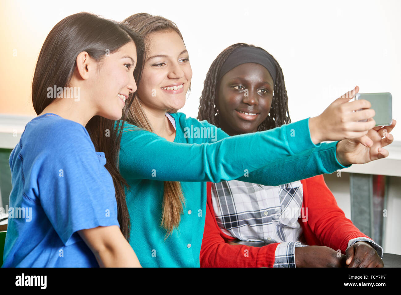 Drei Mädchen im Teenageralter unter ein Selbstporträt in der Schule Stockfoto