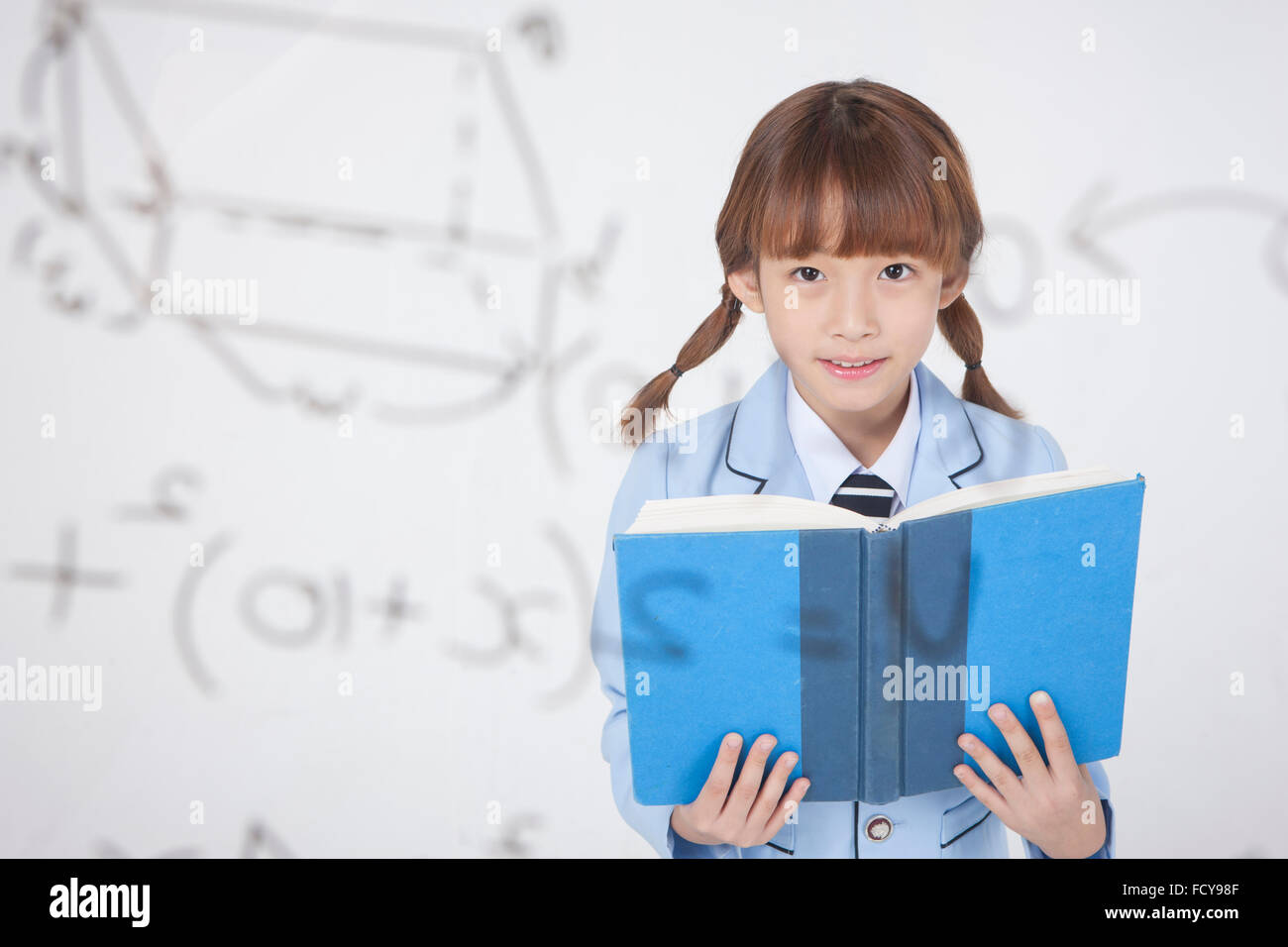 Grundschule Mädchen in Uniform hinter einem transparenten Brett mit Mathe-Formel ein Buch zu lesen Stockfoto