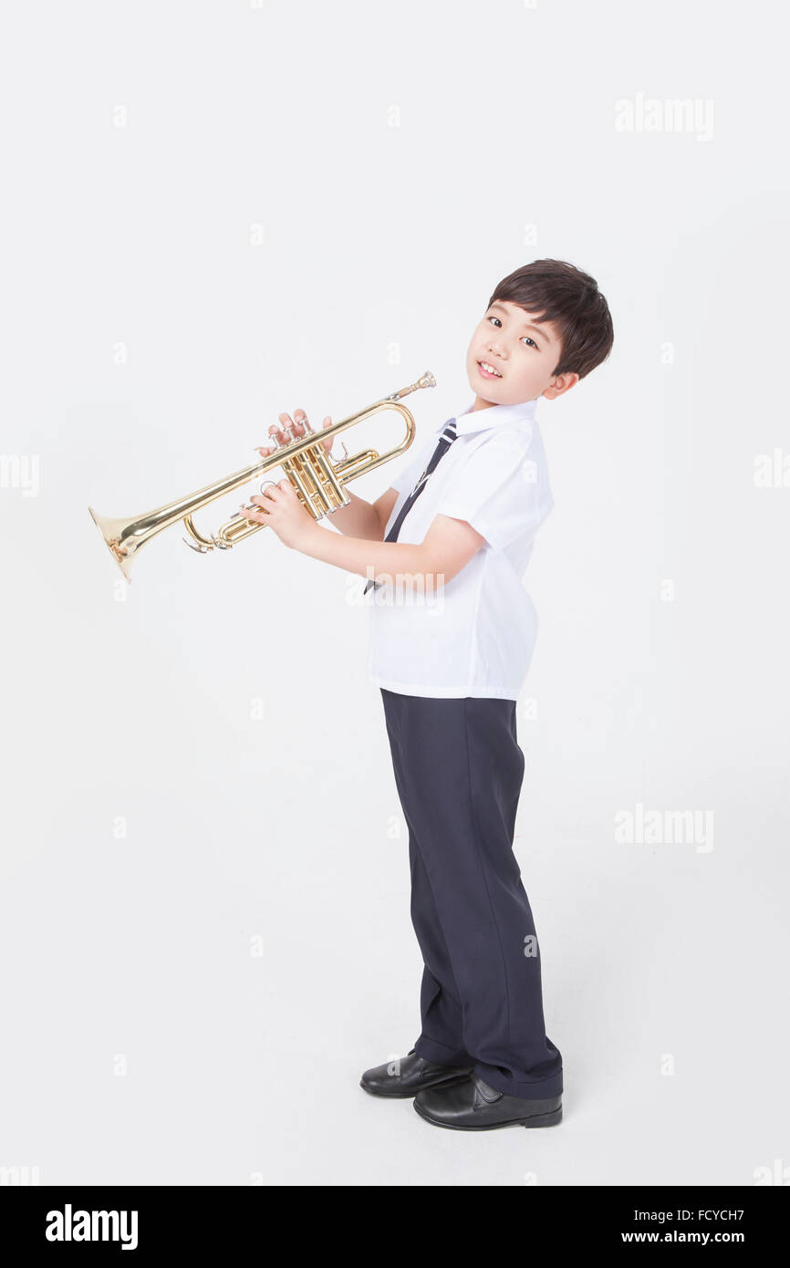 Seite Darstellung eines jungen der Grundschule in Schuluniform stehend mit einer Trompete und starrte nach vorne Stockfoto