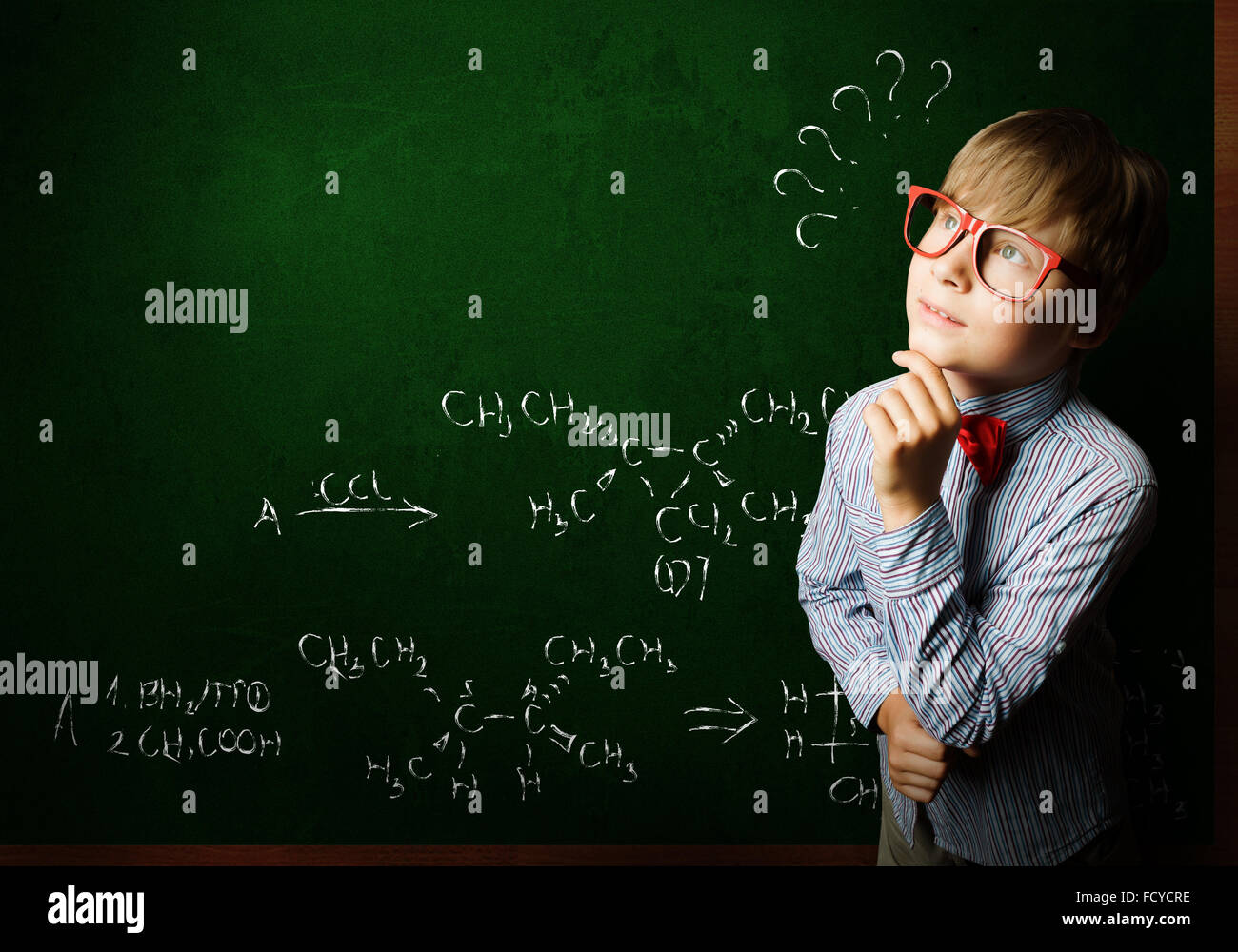 Genie junge im roten Brille in der Nähe von Blackboard mit Formeln Stockfoto