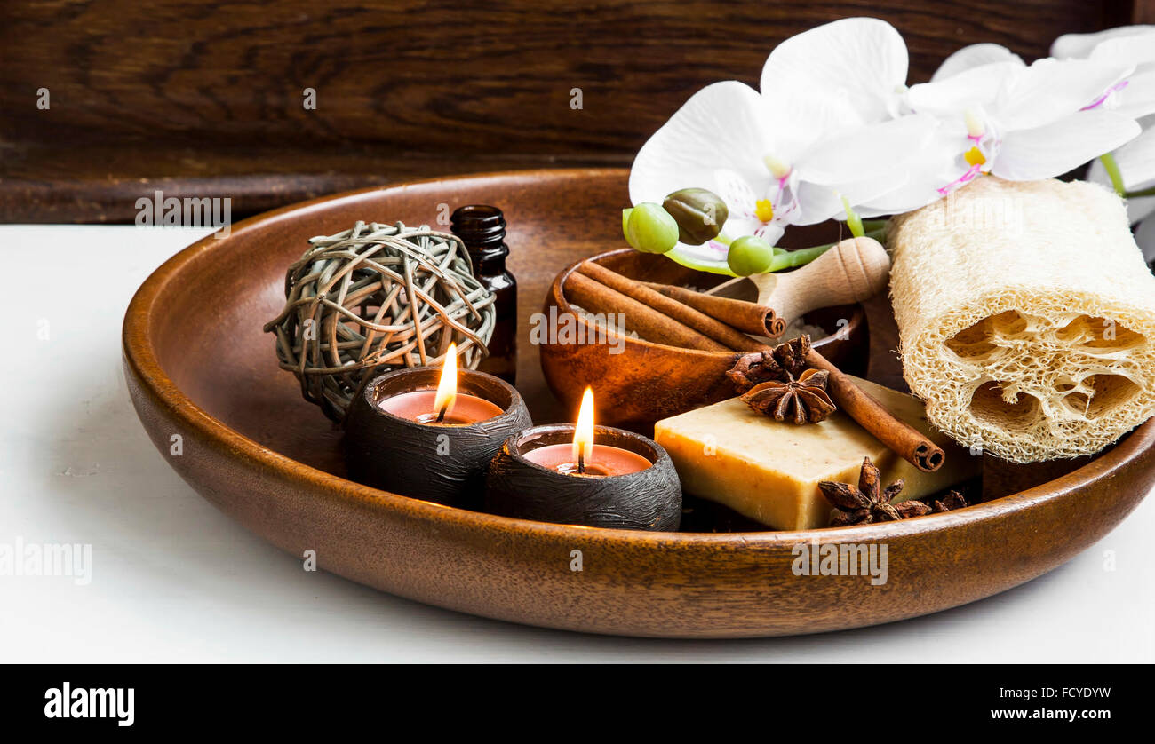 Wellness-Produkte in Holztablett mit weißen Orchideen und Duft Kerzen Stockfoto