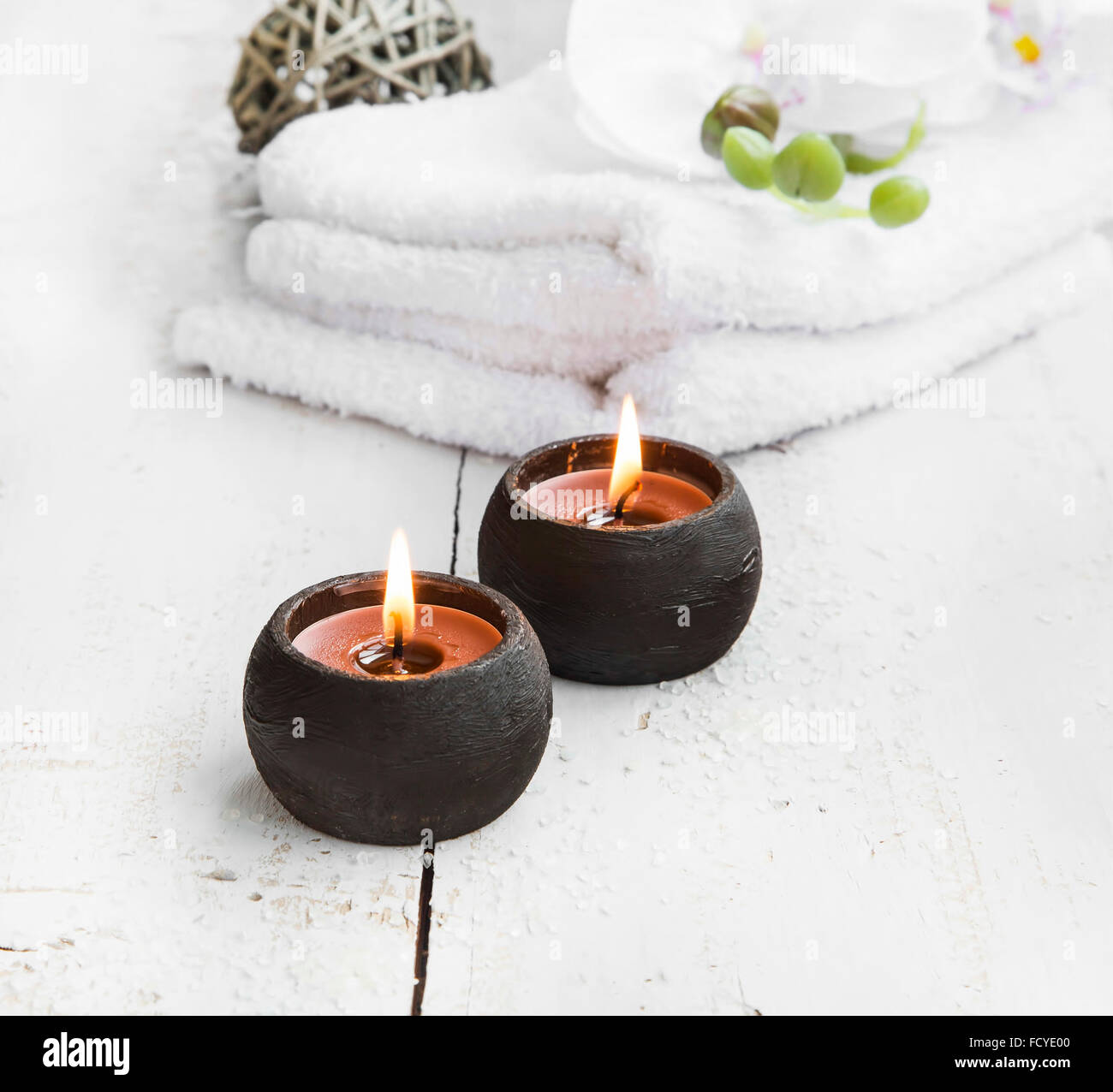 Spa-Stillleben mit brennenden Kerzen, weiße Handtücher und Orchidee Stockfoto