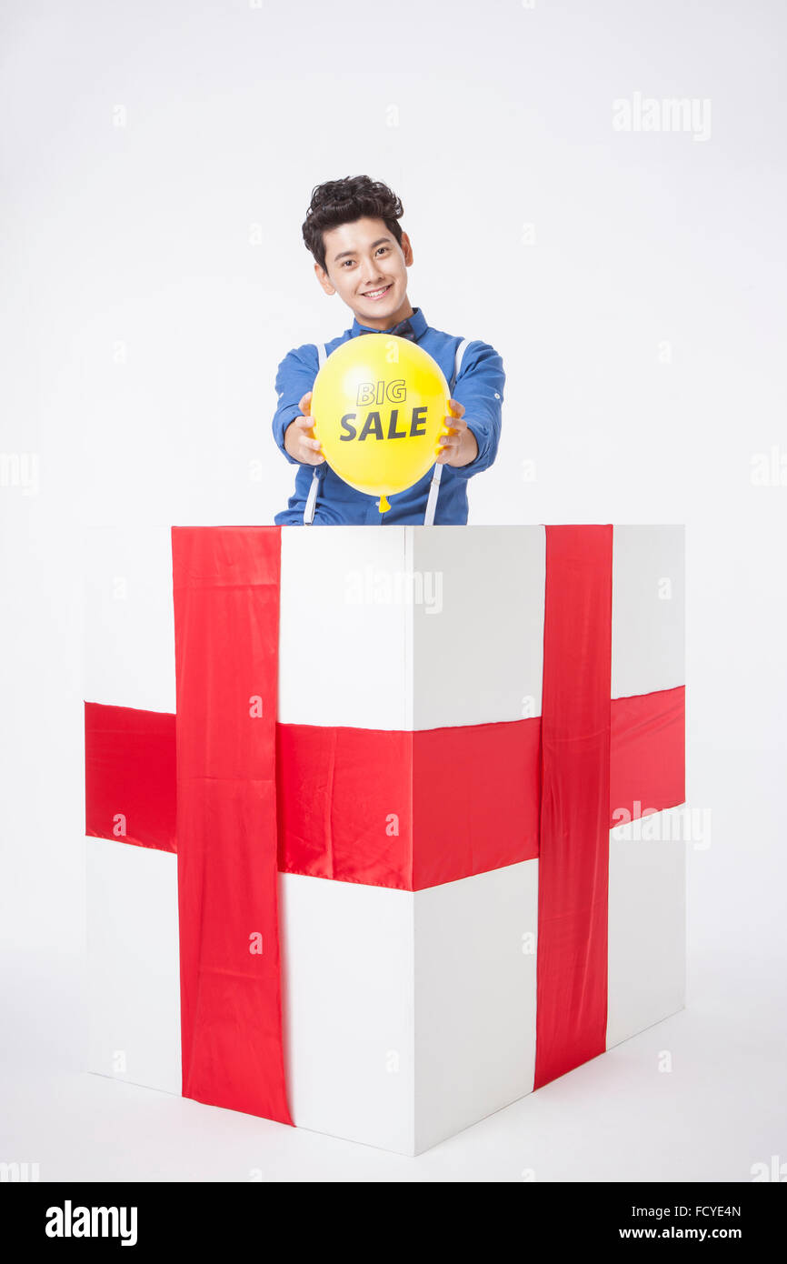 Mann im retro-Stil hält einen großen Verkauf Ballon nach vorne in einer Geschenkbox geliefert Stockfoto