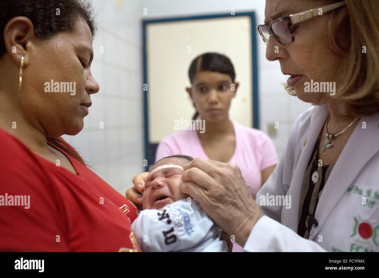 Recife, Brasilien. 21. Januar 2016. Arzt Angela Rocha (R) misst den Kopfumfang des ein-Monat-alte Alexandro Julio, der von seiner Großmutter im Beisein seiner Mutter 16-Year-Old Julie Adriana (C) am Klinikum Oswaldo Cruz in Recife, Brasilien, 21. Januar 2016 gehalten wird. Das Baby leidet unter Mikrozephalie, führt zu einer ungewöhnlich kleinen Kopfumfang und Funktion des Gehirns beeinträchtigt. Das Zika-Virus von Mücken auf schwangere Frauen übertragen wird vermutet, diese Probleme zu verursachen. Allein Brasilien berichtet fast 3900 Fälle. Foto: RAFAEL FABRES/Dpa/Alamy Live News Stockfoto