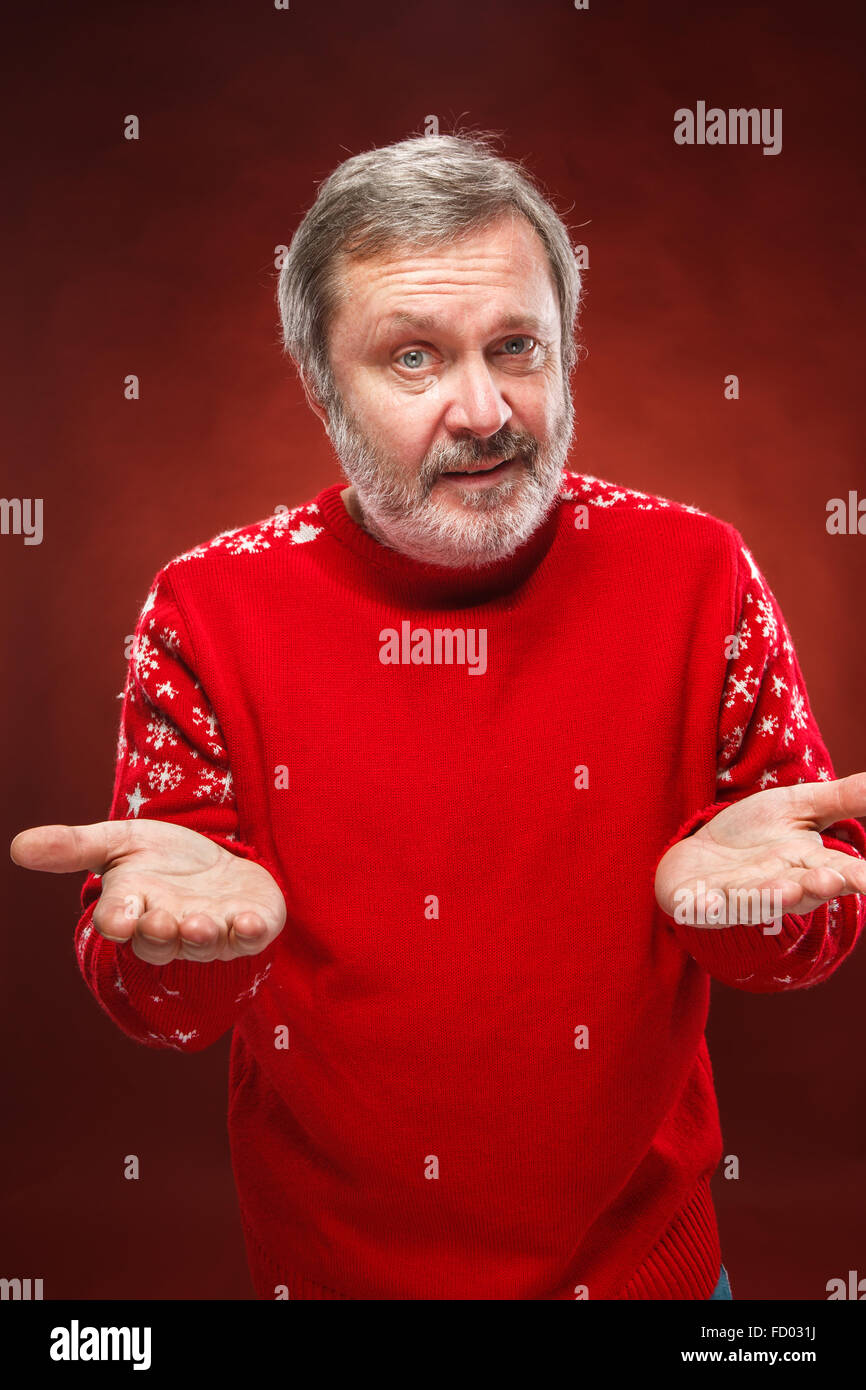 Ältere Menschen Lächeln freundlich Mann im roten Pullover auf einem roten Hintergrund bietet Ihnen etwas Stockfoto
