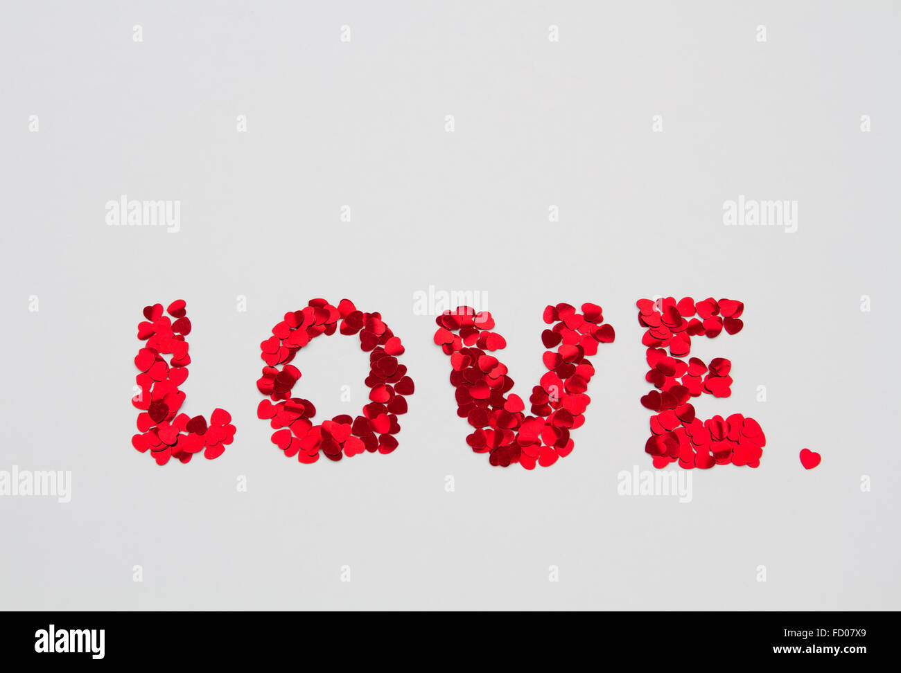 Das Wort Liebe in kleinen Herzen formen und Dekorationen auf einer weißen, isolierten Hintergrund geschrieben. Stockfoto