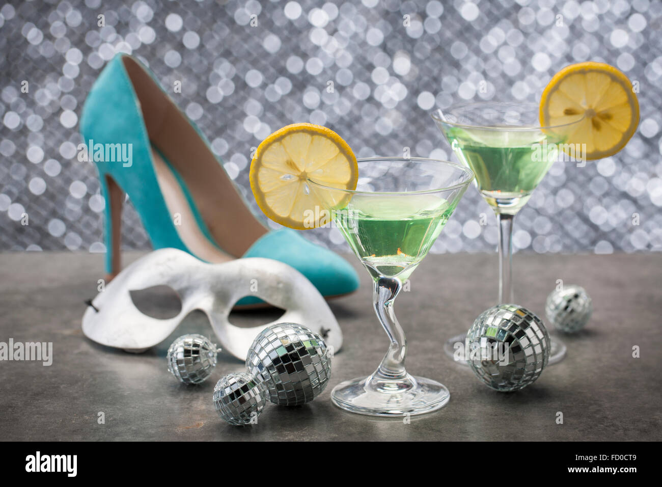 Grüne Cocktails mit Zitrone auf Tisch mit high-Heel, Maske und Spiegelkugeln Stockfoto