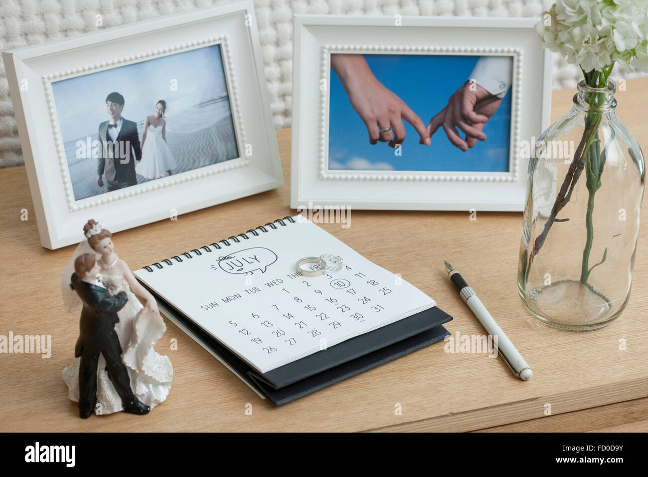 Hochzeit Bilder in Rahmen platziert auf einer Schublade mit Kalender und eine Vase mit Blumen Stockfoto