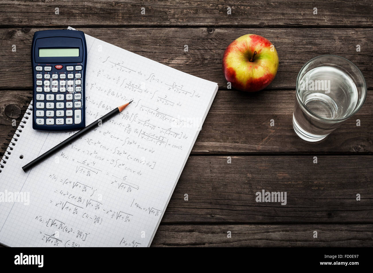 Gesunden Lernkonzept - Taschenrechner und Bleistift über ein Blatt Papier mit mathematischen Formeln, einen Apfel und ein Glas frisch Stockfoto