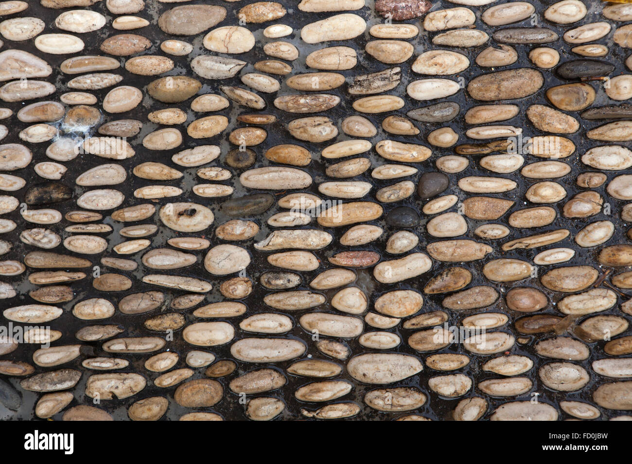 Kopfsteinpflaster gemacht von gerundet Flusskiesel in Córdoba, Andalusien, Spanien. Hintergrundtextur. Stockfoto