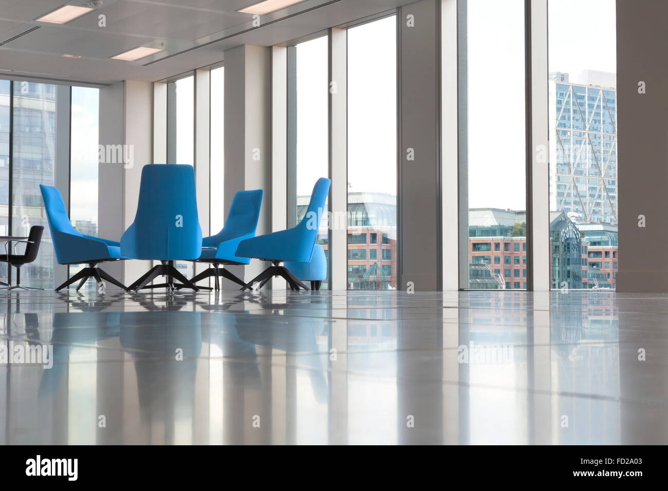 Moderne Büroeinrichtung mit Glasfenster und bequeme blaue Sessel in der Ecke Stockfoto