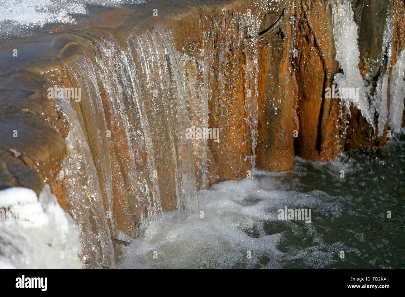 Schöne kleine Winter Creek Wasserfall fotografiert Closeup auf einem Hintergrund von Schnee und Eis Stockfoto