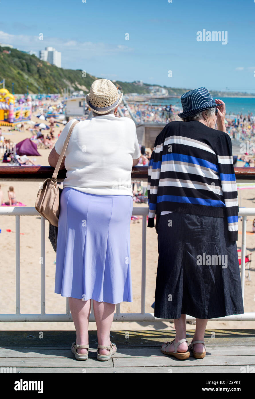Zwei pensionierte Damen sehen Sie die Touristen auf einer überfüllten Strand von Bournemouth UK Stockfoto