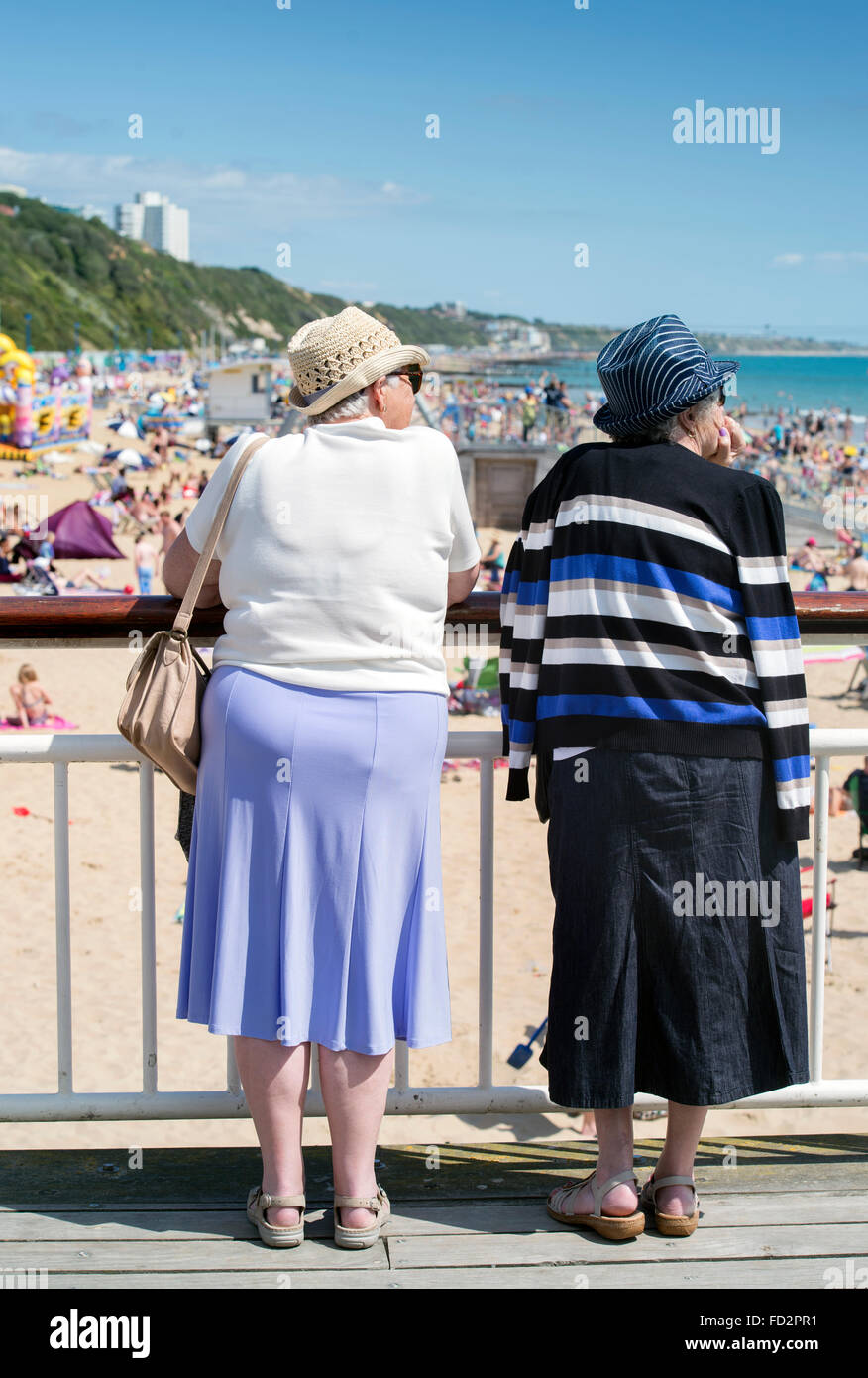 Zwei pensionierte Damen sehen Sie die Touristen auf einer überfüllten Strand von Bournemouth UK Stockfoto