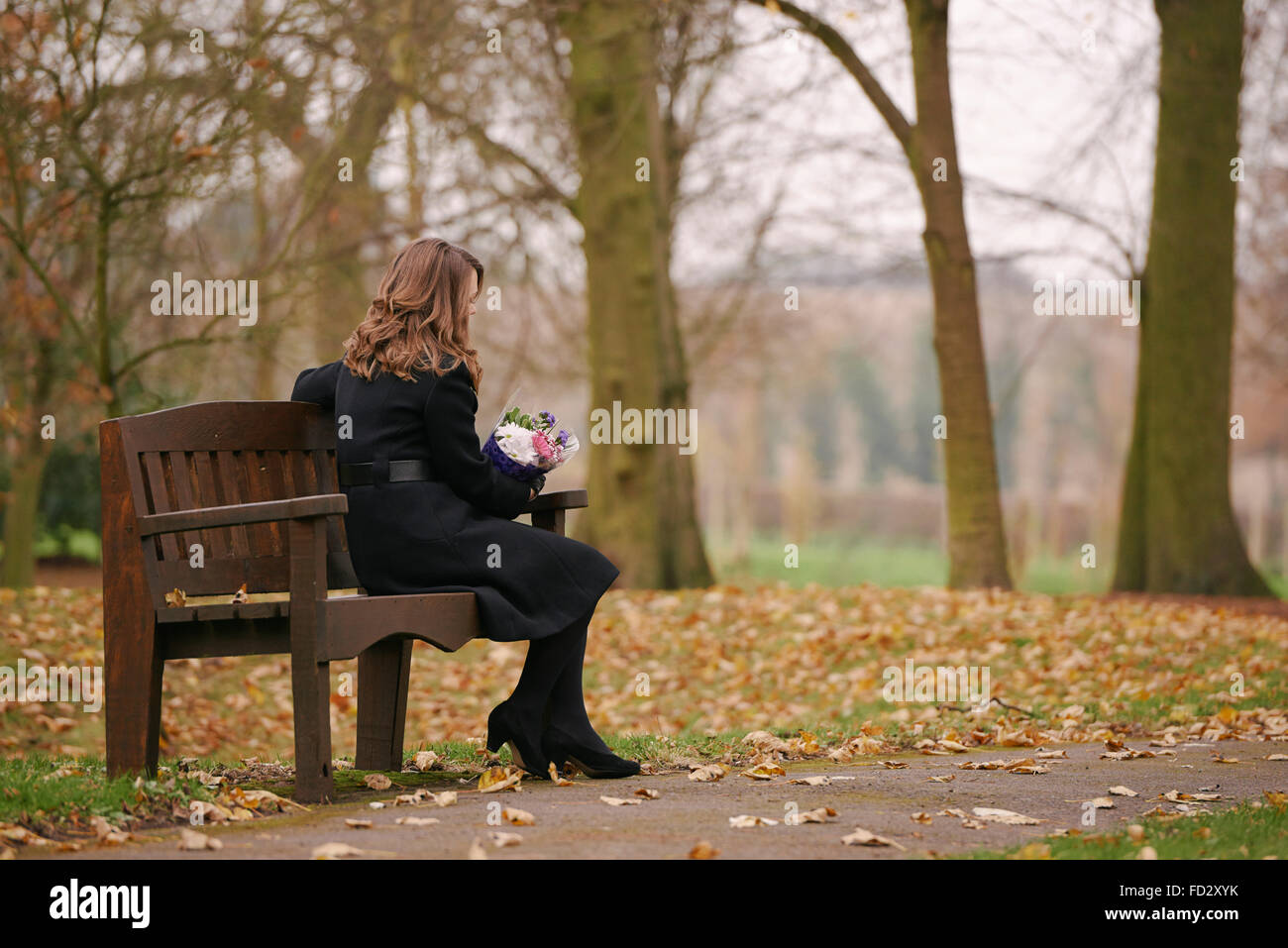 Trauernde Frau saß auf der Bank bei einer Beerdigung Dienst (inszenierten) Stockfoto