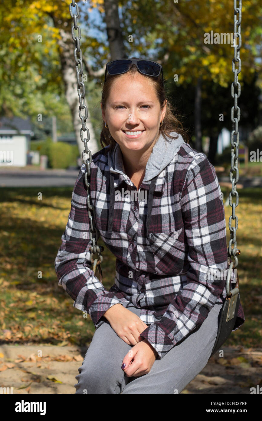 Lächelnde Frauen auf einer Schaukel im Herbst Stockfoto