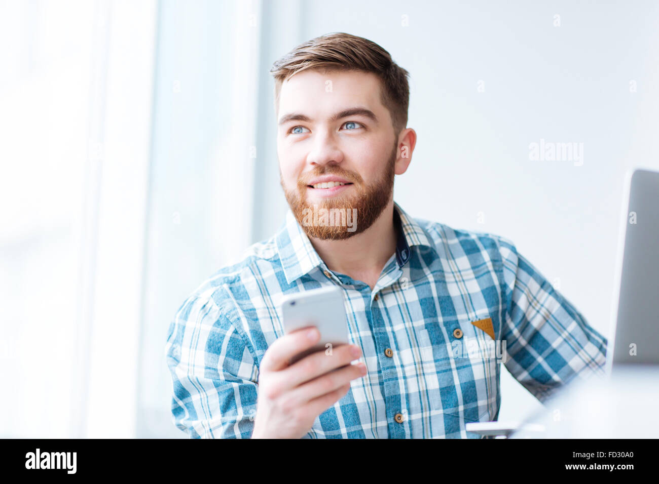 Porträt von ein glücklicher Mann mit Smartphone und wegsehen Stockfoto