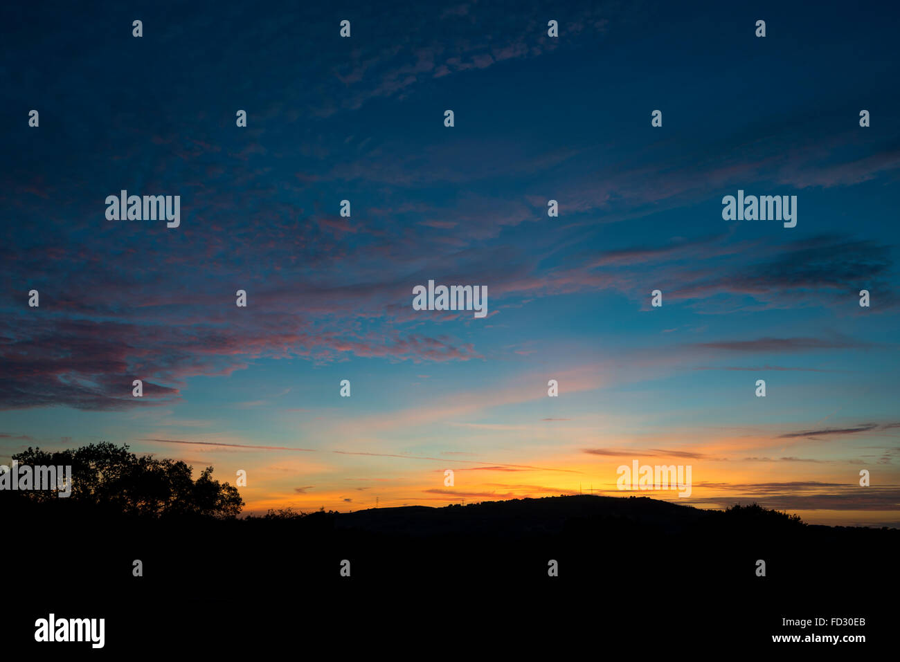 Einen schönen September-Sonnenuntergang mit hohen Wolkenfetzen das letzte Sonnenlicht fangen. Stockfoto