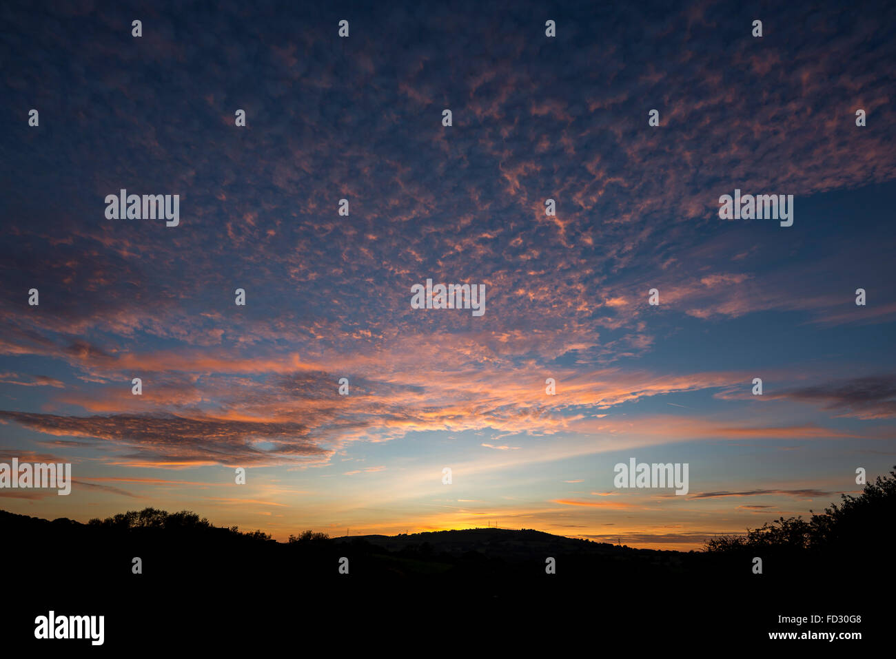 Einen schönen September-Sonnenuntergang mit hohen Wolkenfetzen das letzte Sonnenlicht fangen. Stockfoto