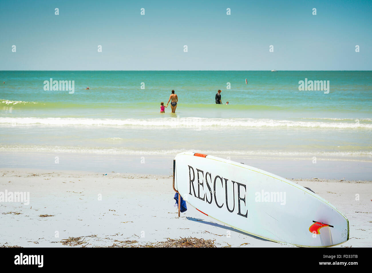 Eine Rettung Surfbrett im Anschlag vor der Strandwache mit Menschen spielen im flachen Wasser blau Siesta Key Beach Stockfoto