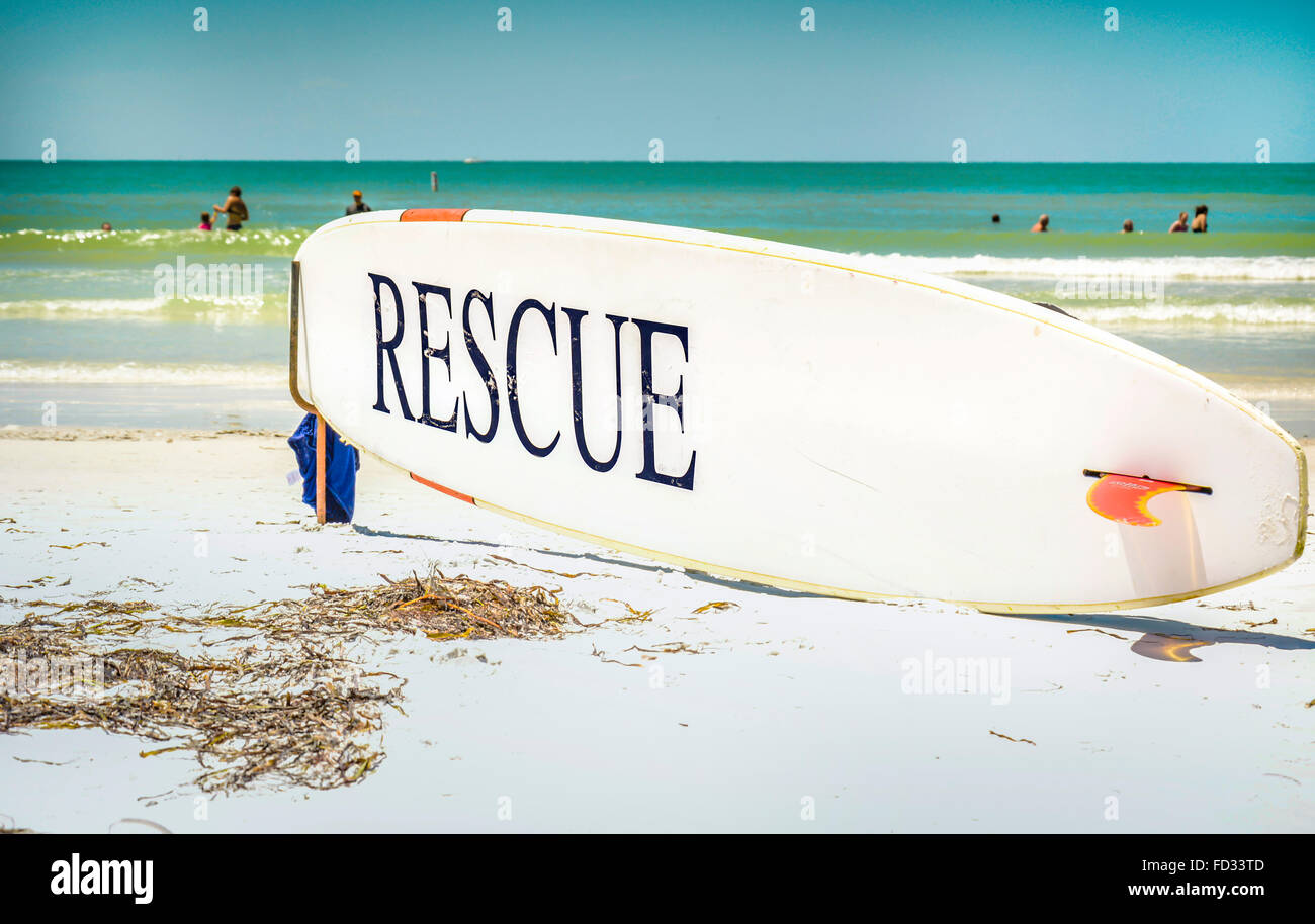 Eine Rettung Surfbrett im Anschlag vor der Strandwache mit Menschen spielen im flachen Wasser blau Siesta Key Beach Stockfoto