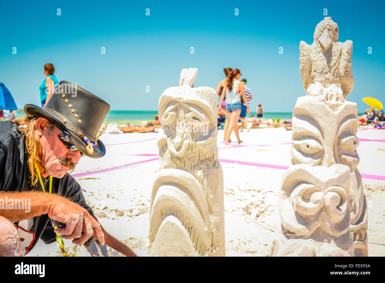 Ein Mann arbeitet auf einer aufwendigen Sandburg Konstruktion erinnert an Totempfähle während eines Wettkampfes am Siesta Key Beach, FL Stockfoto